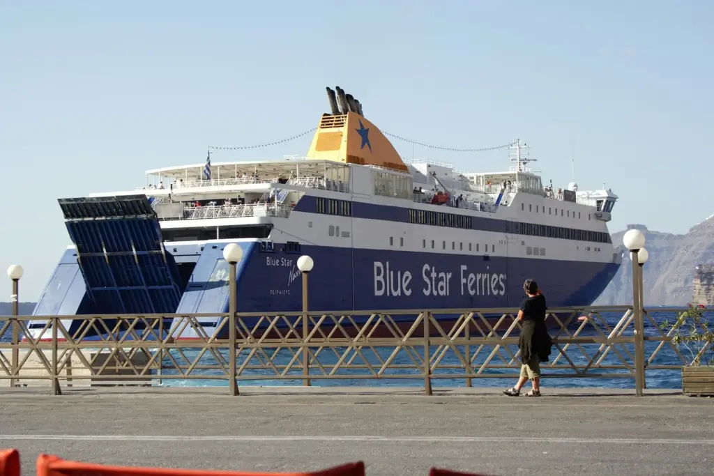 The Blue Star Naxos ferry moored at the quay in Athinios port with a traveler watching from the railing