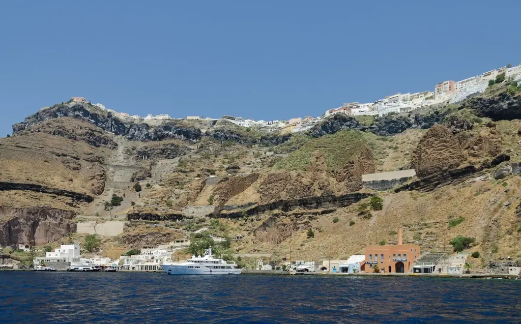 Fira's white buildings along the top of the caldera cliff, with the cable car line and the Old Port at the waterline