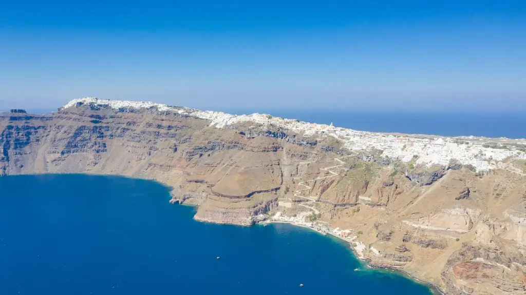 Aerial view of Fira's cliffs with the Old Port harbor at the waterline below the town