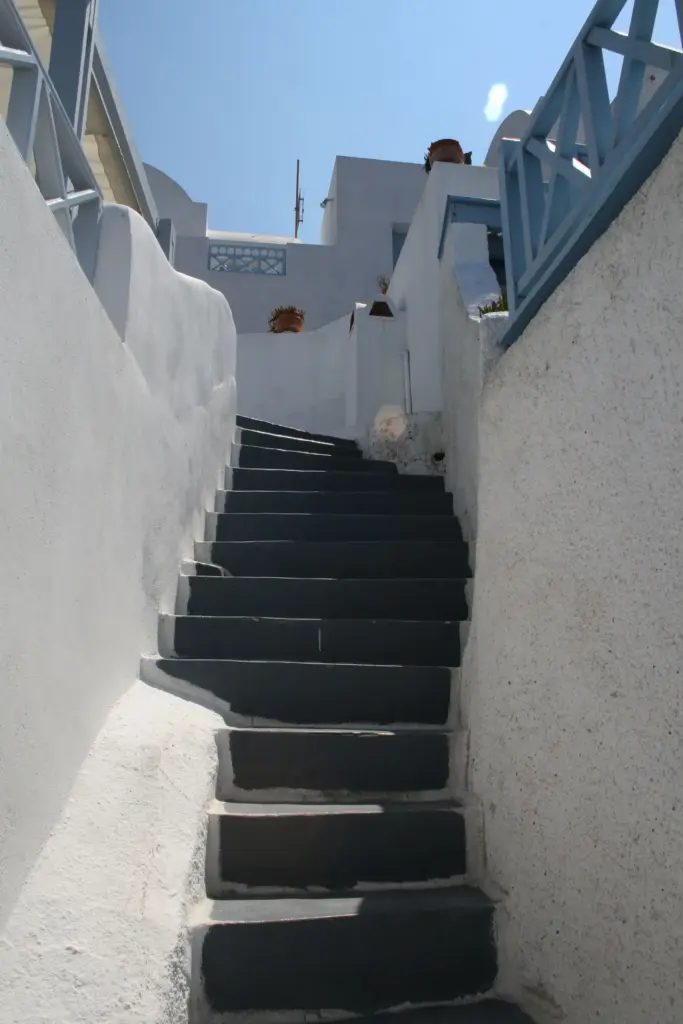 A narrow flight of whitewashed stone steps climbing between walls in Fira