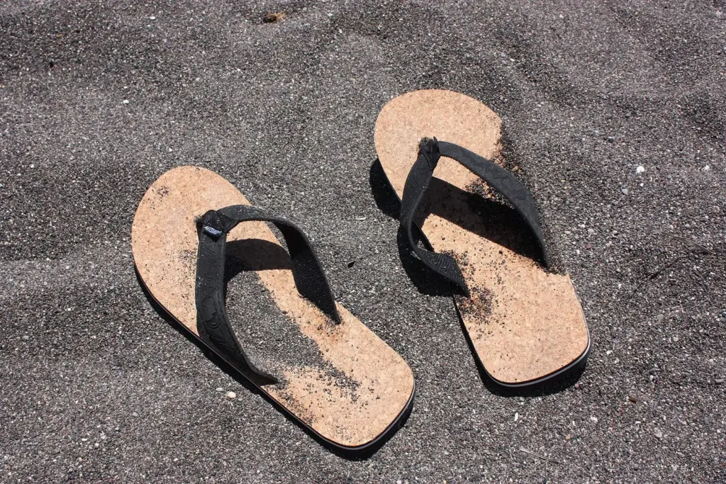 A pair of cork flip-flops on hot black volcanic sand in early summer