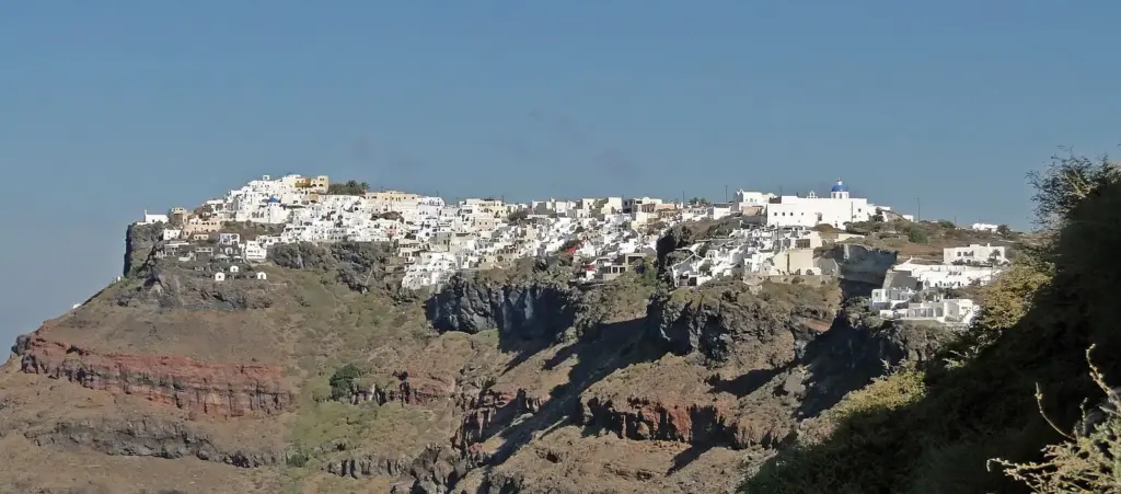The village of Imerovigli spread along the top of the caldera cliff, seen from Fira