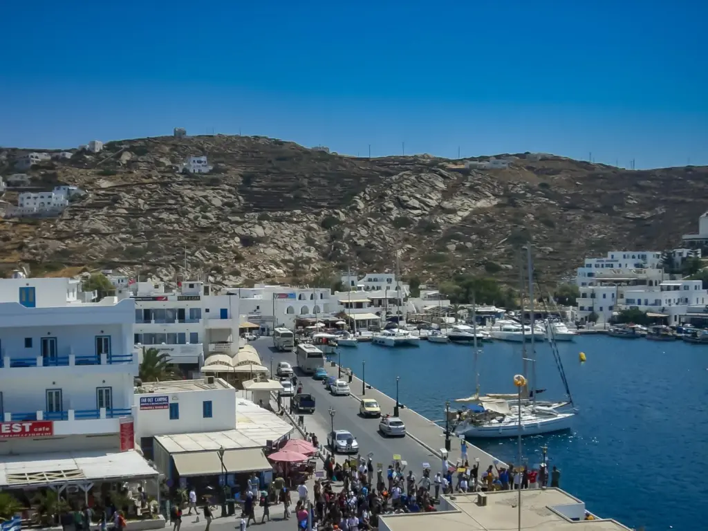 The harbor at Ios with boats moored along the quay and white houses on the hillside