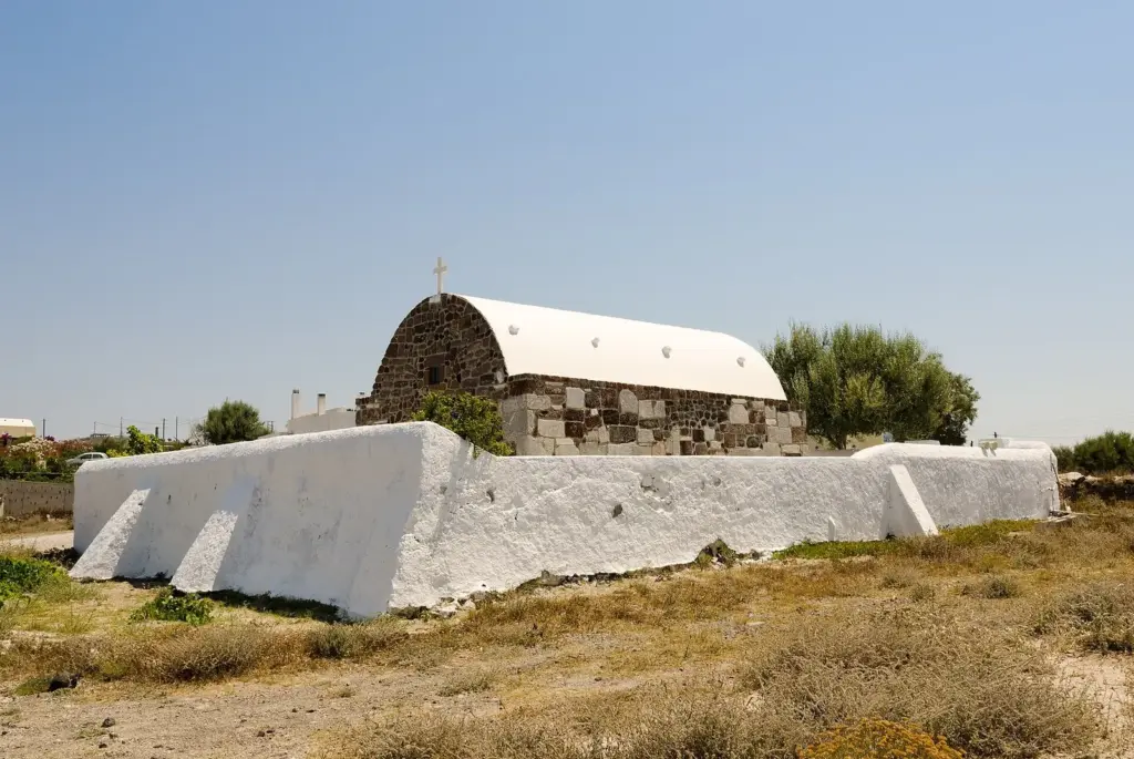 A small whitewashed chapel with a stone front and a curved white roof in the countryside near Megalochori