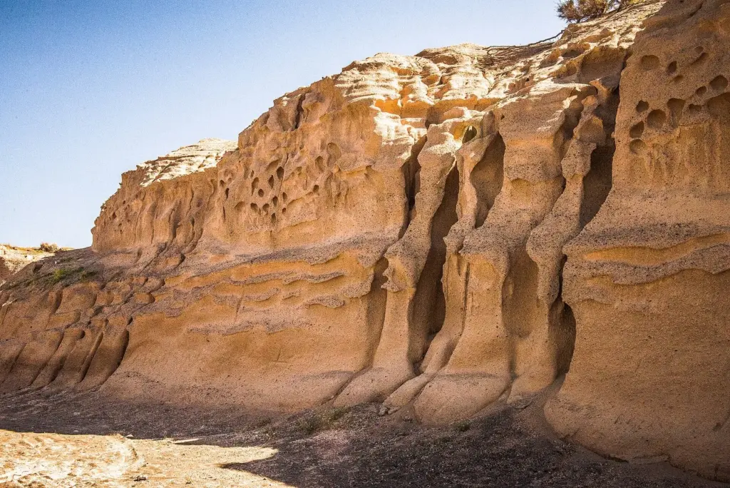 Honey-colored sandstone cliffs carved by the wind into hollows near Monolithos
