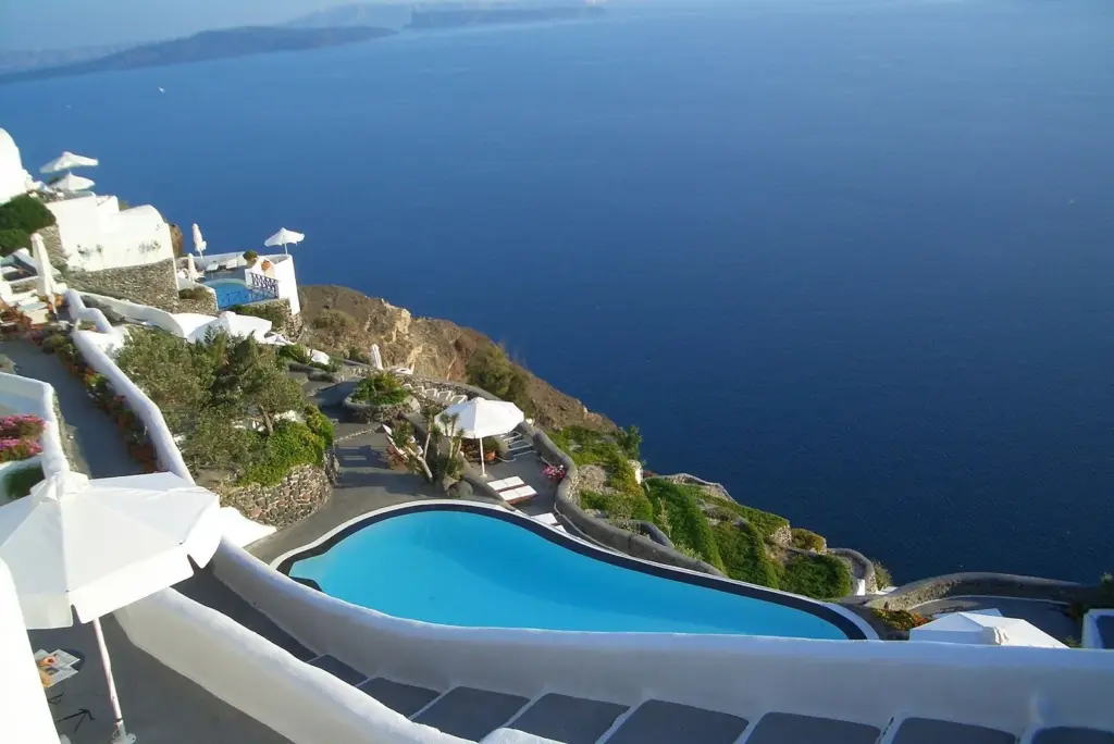 A curved swimming pool on a terraced cliffside property above the caldera in Oia