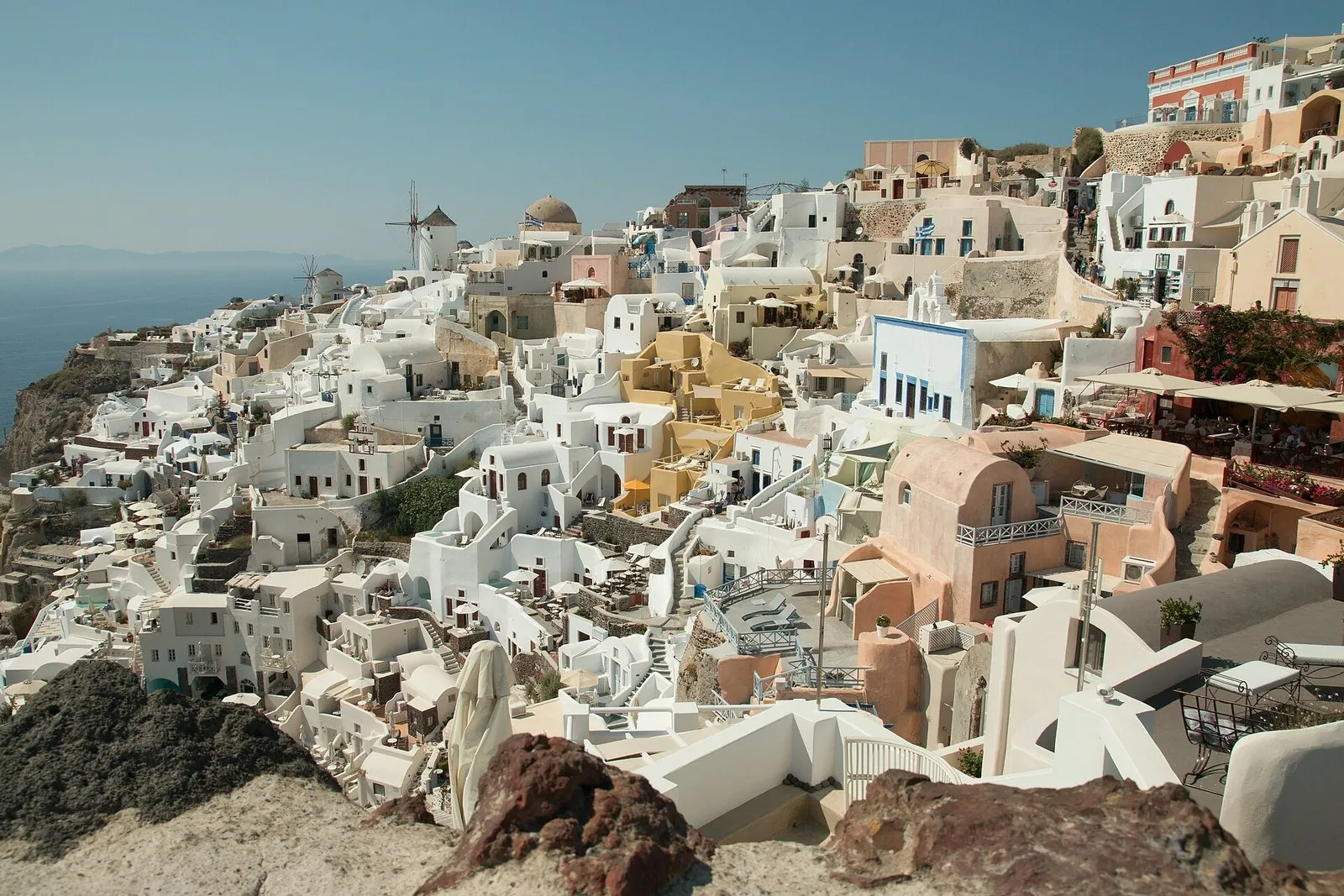Oia Santorini seen from the castle: white cave houses, windmills and pastel mansions spilling down the caldera cliff