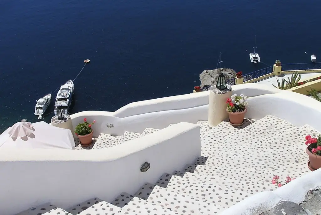 Whitewashed stairs leading down between terraces toward the caldera in Oia
