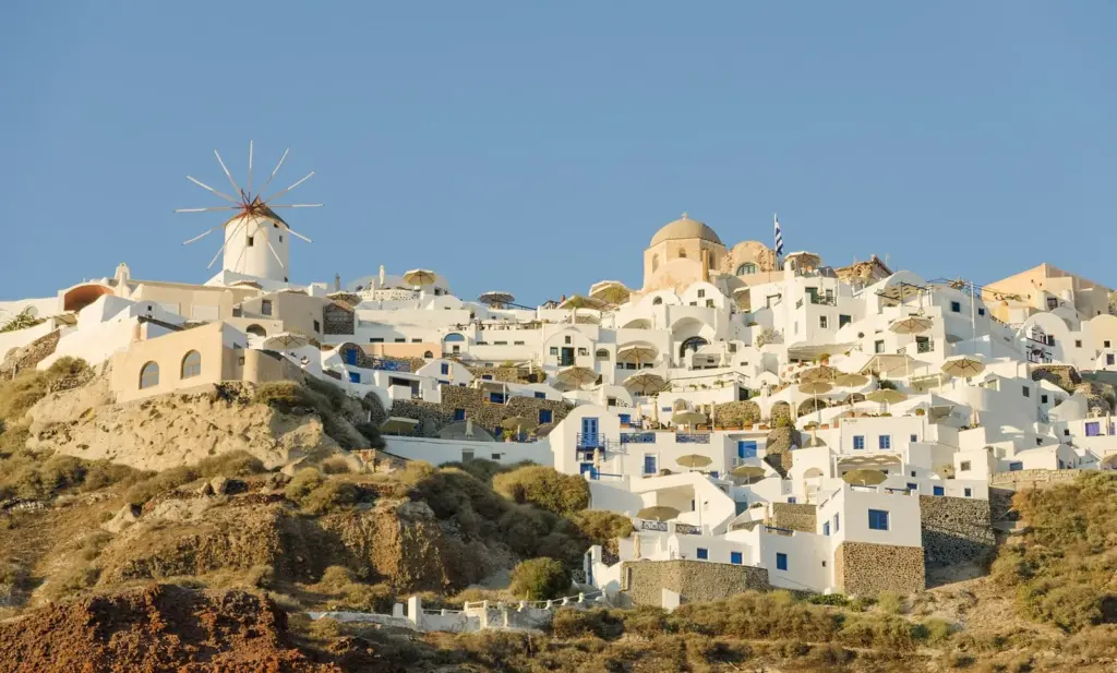 Oia's white houses and domed churches spread along the ridge, with a windmill on the skyline