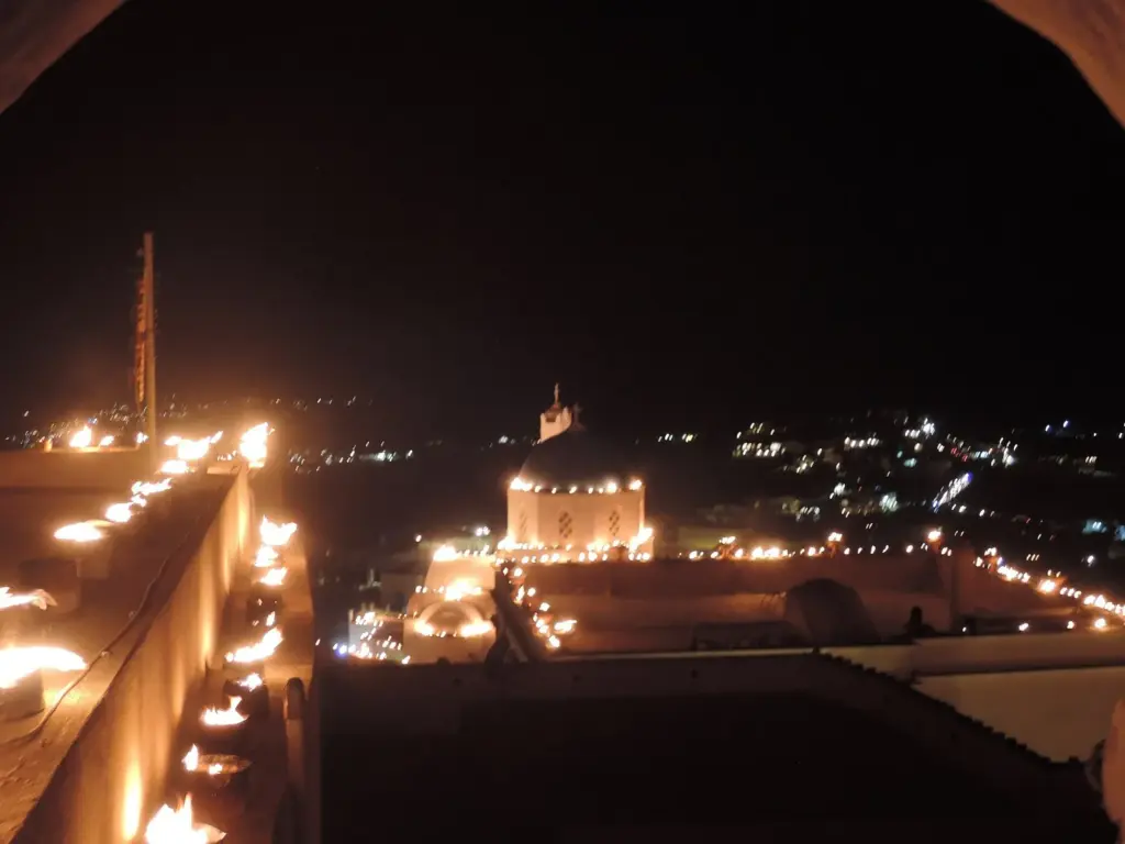 Pyrgos at night lit by rows of small flames along its rooftops and walls for Greek Easter