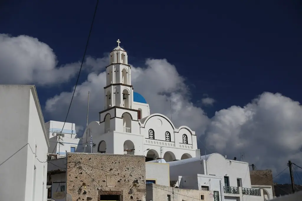 A white bell tower and blue-domed church rising above the rooftops of Pyrgos