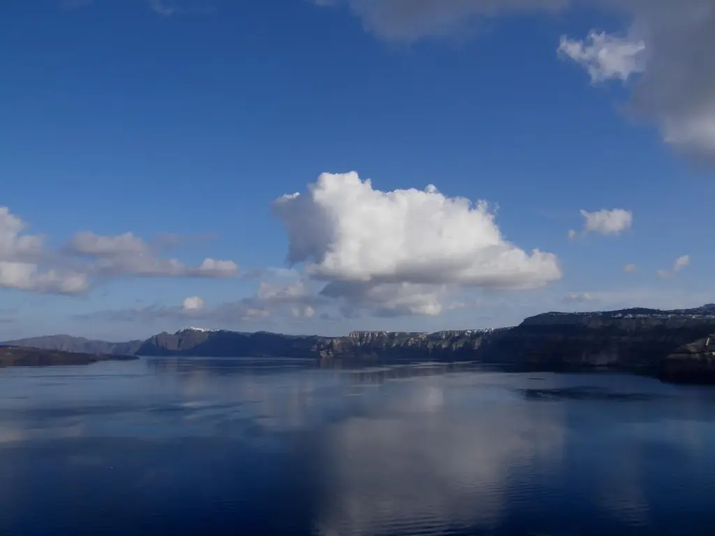 The calm caldera and its cliffs under white winter clouds, seen from Akrotiri village