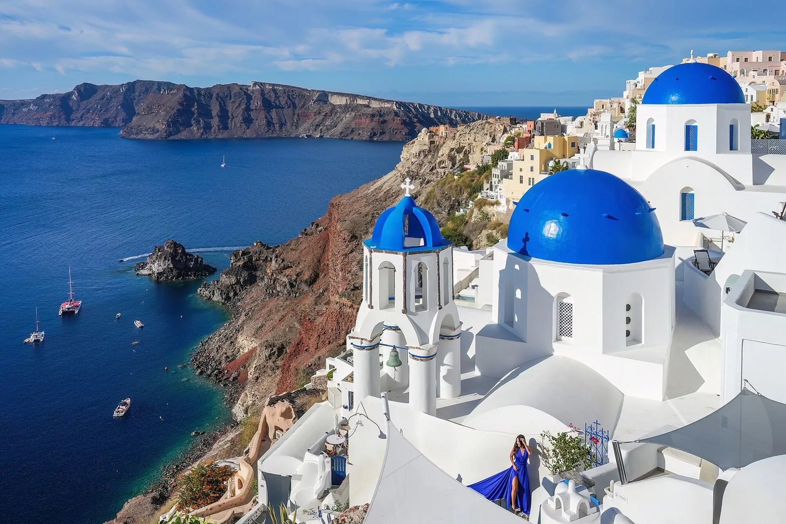 Things to do in Santorini: the three blue domes of Oia above the caldera cliffs and the sea