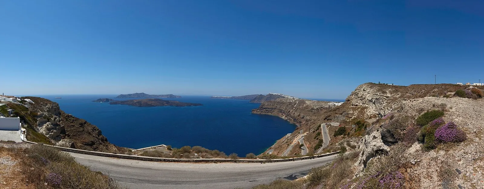 A road curving along the caldera rim above the flooded crater, the kind of route you drive when getting around Santorini