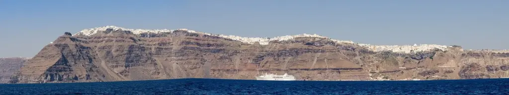 The caldera rim seen from the sea, with the white villages of Imerovigli, Firostefani and Fira strung along the cliff top