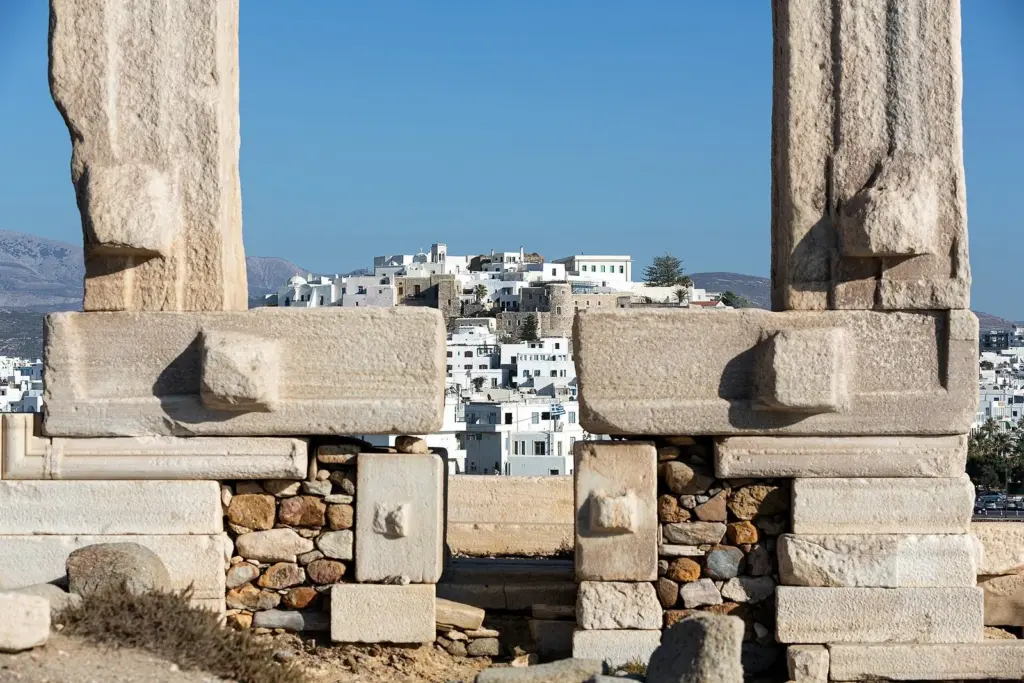 The tall marble gateway of the Portara framing the white houses of Naxos town