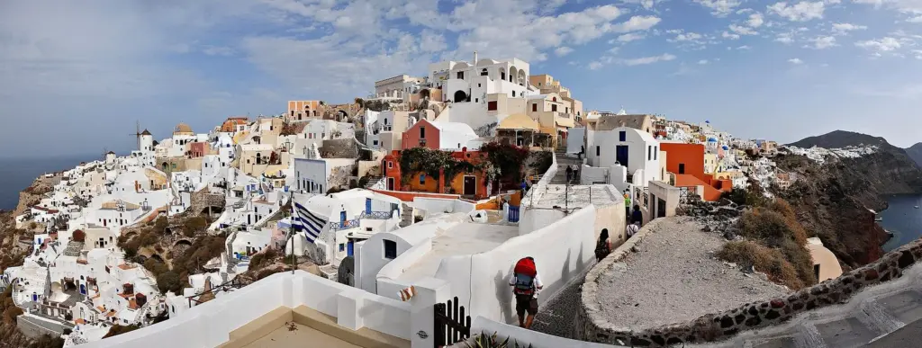 Panorama of Oia's white and colored houses stepping down the hillside above the caldera