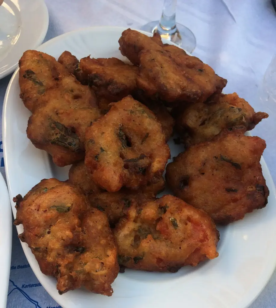 A plate of golden-brown tomato fritters flecked with herbs